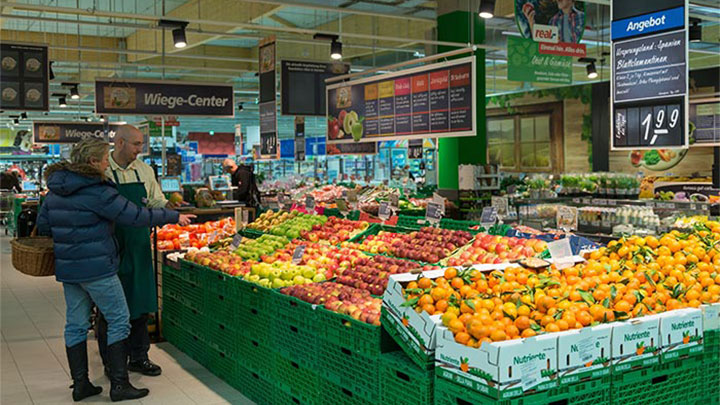 Клиенти разглеждат плодовете в Real с осветление за супермаркети от Philips