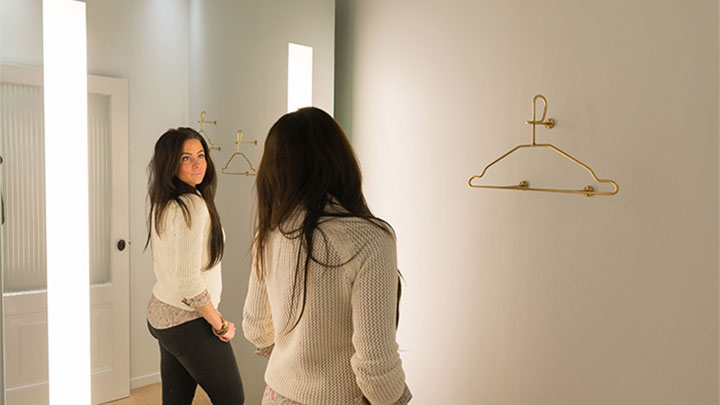 Клиентка на SuperTrash се оглежда в огледалото Philips AmbiScene, настроено на „дневна“ светлина