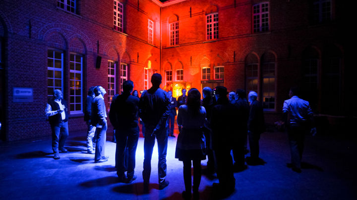Голяма група хора обсъжда пред красиво осветена сграда в Търнхаут, Белгия на семинар, организиран от Philips
