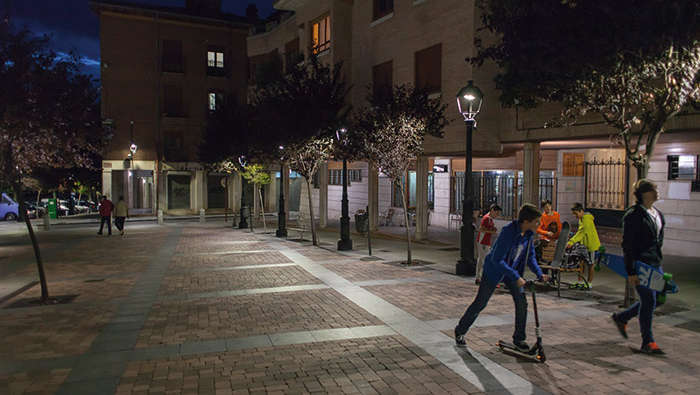 Деца играят на площад през нощта с осветление от Philips