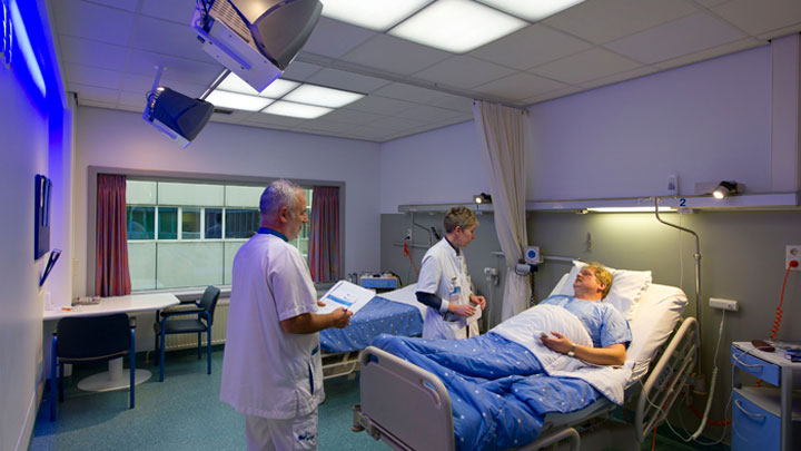 Лекари се грижат за пациент в стая със система за осветление Philips Healwell
