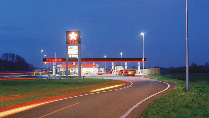 Бензиностанция на Texaco край магистралата, осветена атрактивно в здрача – впечатляващо външно осветление