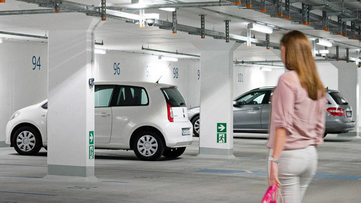 Жена върви към автомобила си в добре осветен подземен паркинг 
