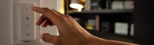 "Интелигентен LED димер на Philips с ръчно регулиране, контролиращ осветлението в уютна всекидневна с рафтове за книги."